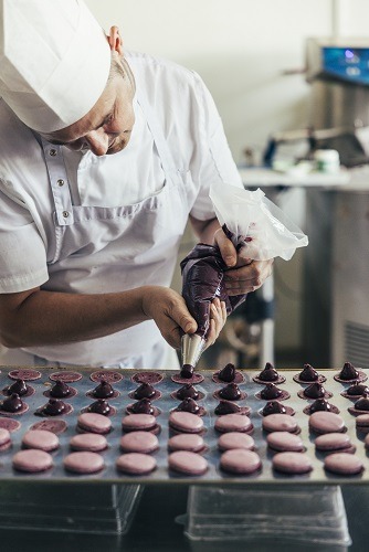 Serge Maranzana von Pâtisserie Élysée füllt handgemachte Macarons mit Ganache in der Backstube in Hannover