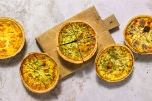 Frisch gebackene Quiches der Pâtisserie Élysée – Juli-Angebot mit Auswahl an Quiche Lorraine, Ratatouille, Spinat und Gemüse-Lachs